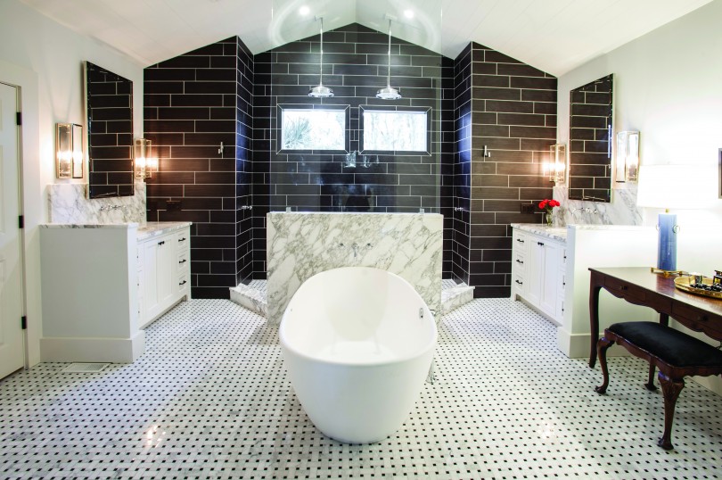 A white, tiled bathroom. The bathtub sits prominently in the center of the room. very well lit, with white marble and black tile in the background