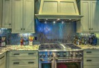 a kitchen with a stainless steel kitchen and silver painted cabinets and drawers. It sits atop a red wood flooring.