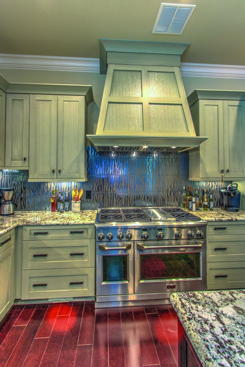 a kitchen with a stainless steel kitchen and silver painted cabinets and drawers. It sits atop a red wood flooring.