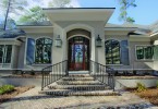 steps lead to wood front door with a large window in its center.