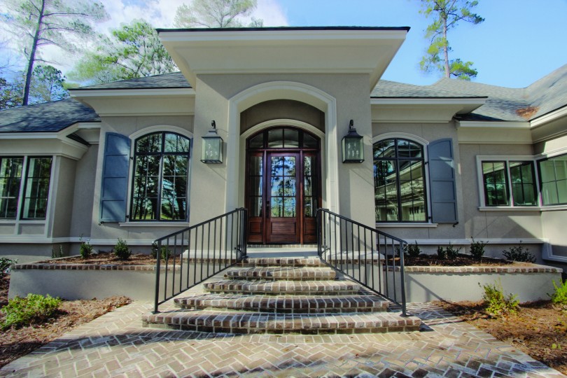 steps lead to wood front door with a large window in its center.