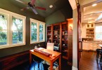 a nook in a home with wood floors, a desk, and wooden shelves. Lots of functional storage space.