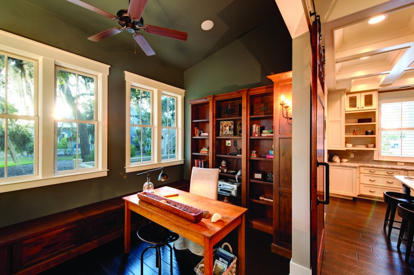 a nook in a home with wood floors, a desk, and wooden shelves. Lots of functional storage space.